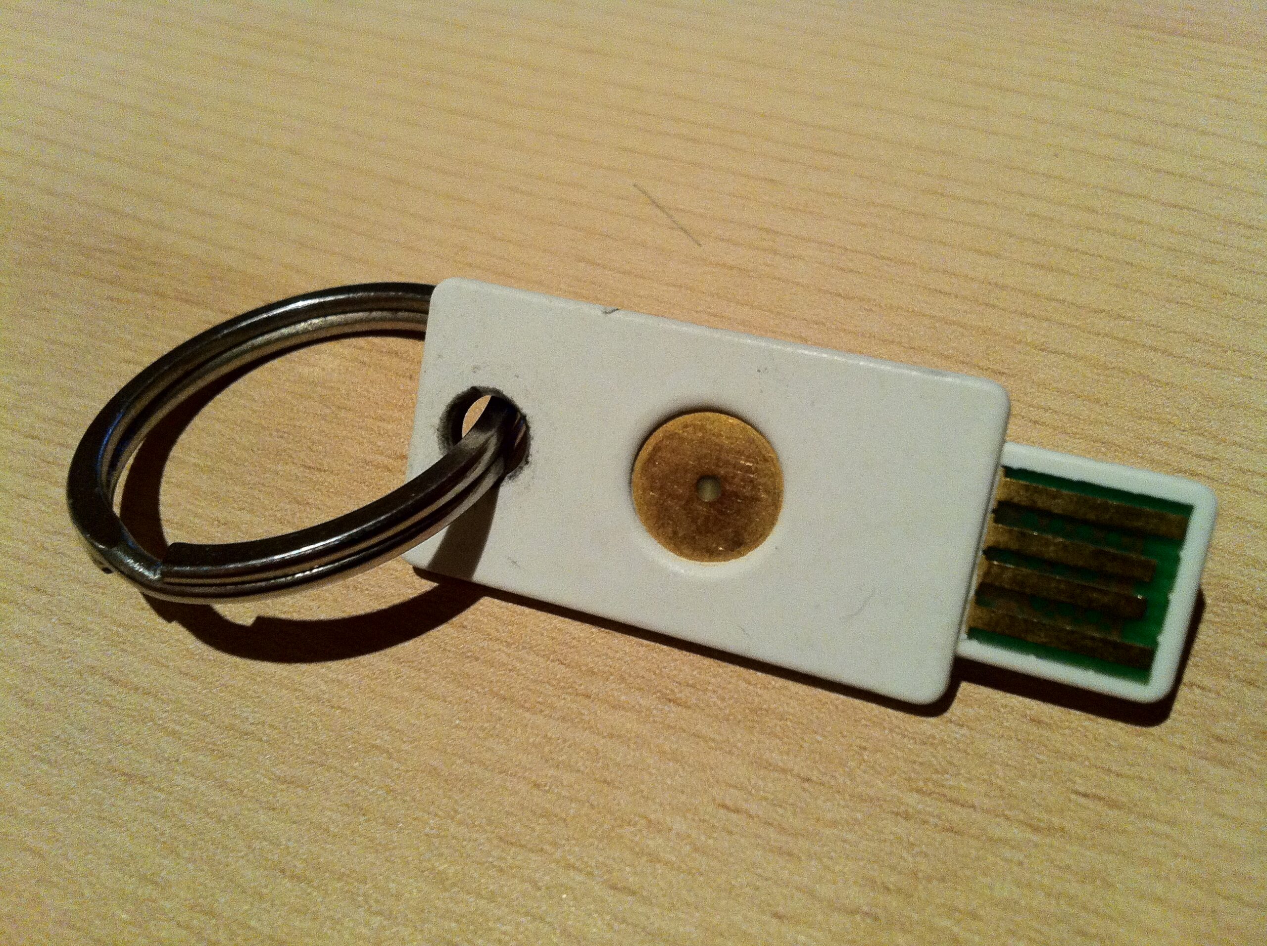 A white YubiKey USB authentication token with an exposed USB connector.